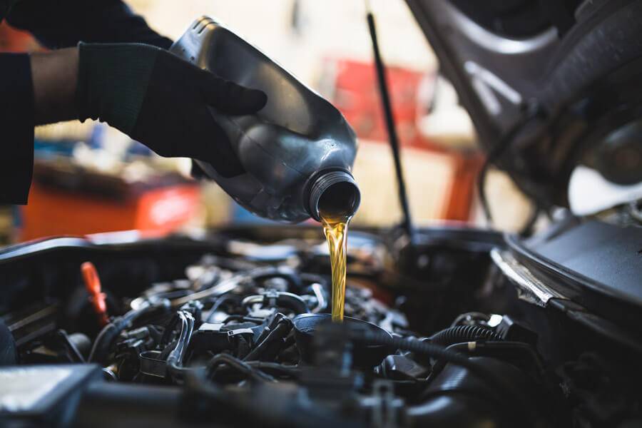mechanic pouring oil into engine