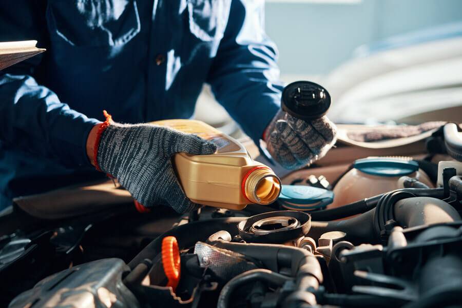 mechanic pouring oil into car